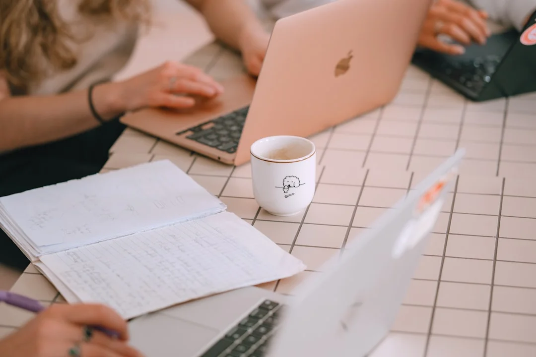 Un espace de travail moderne où des mains analysent des données marketing sur un ordinateur portable et des documents papier.